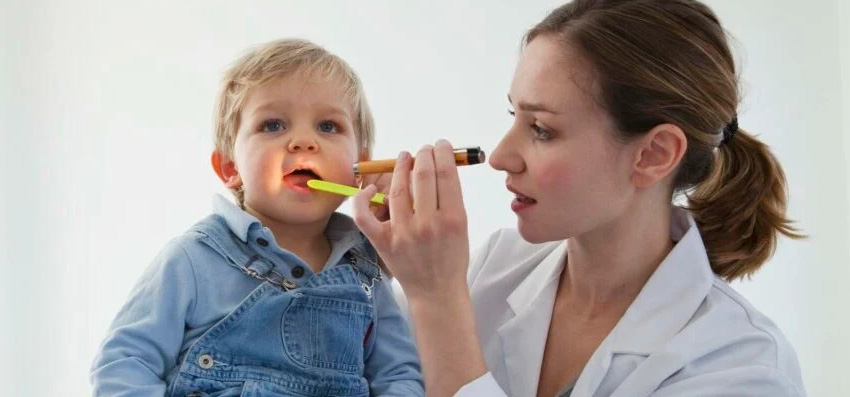 Female doctor checking childs mouth