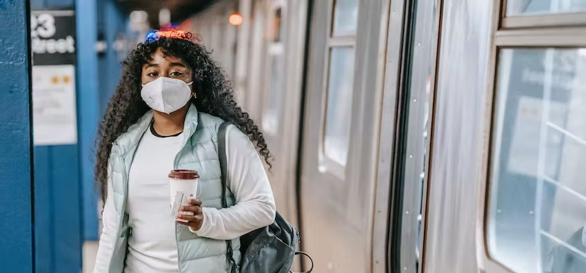 younbg woman on train platform wearing a mask to protect from infection and reduce transmission