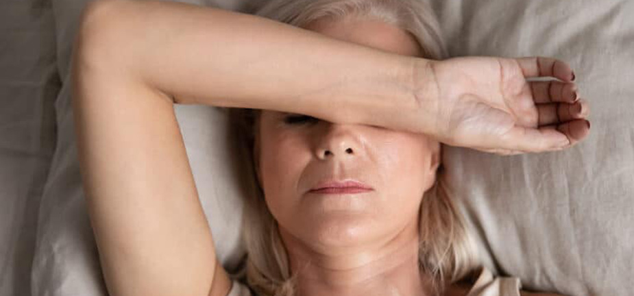 Woman with arm across face suffering some pain and discomfort