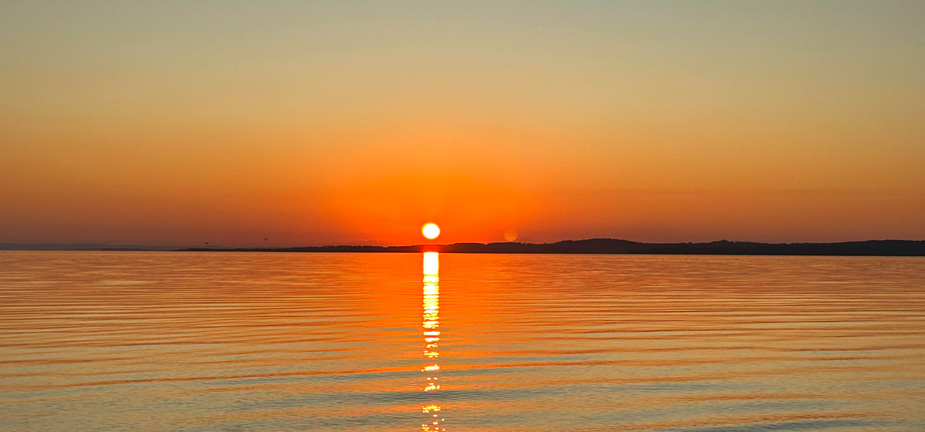 Sunsetting over the water with mountains in the background