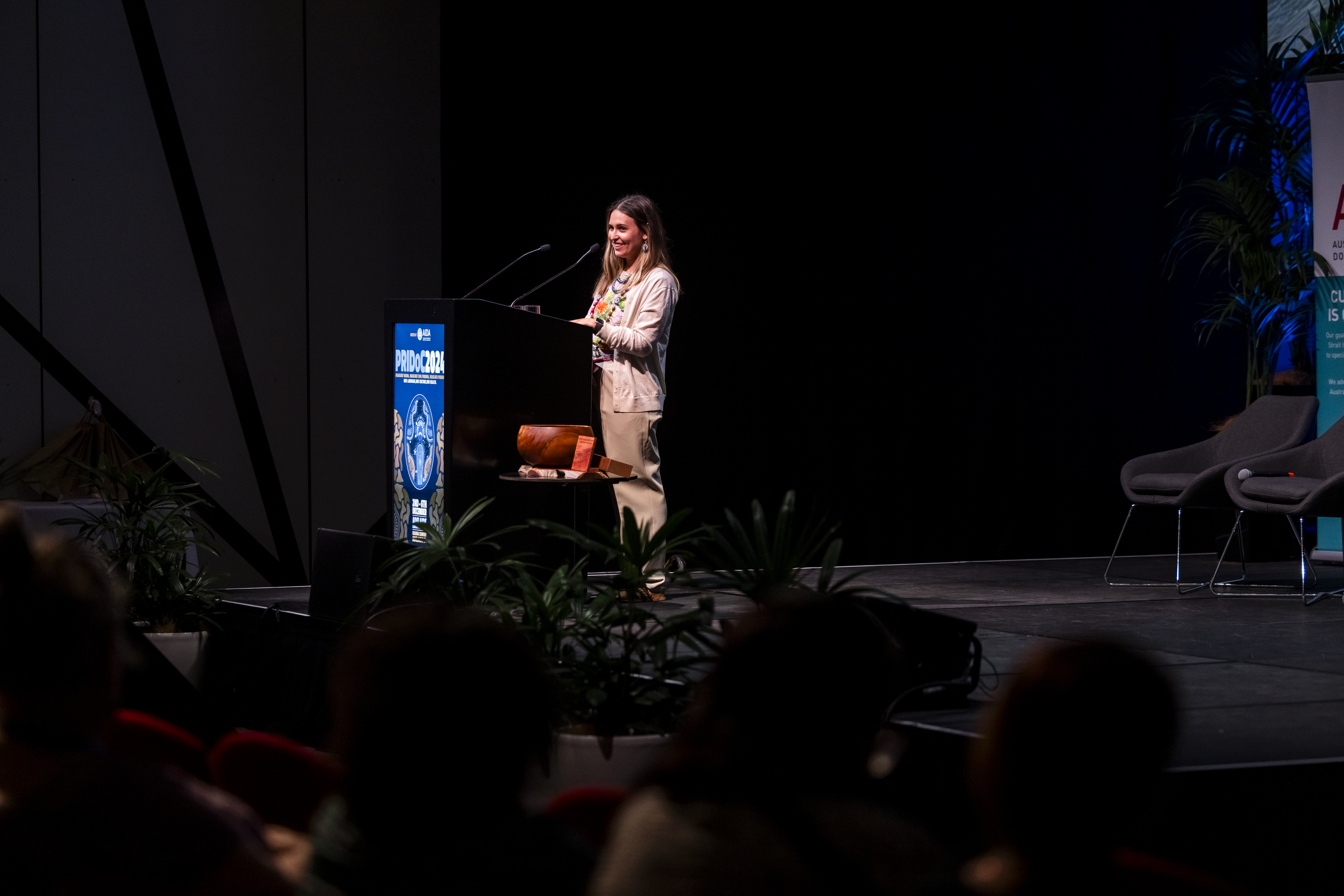 Dr Loyola Wills speaking in a plenary session at PRIDOC December 2024 “Sensing that Salt Water – The Journey Home , A Spoken Yarn”